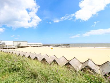 A beach with a pier and grass at The Mill House Apartment in 