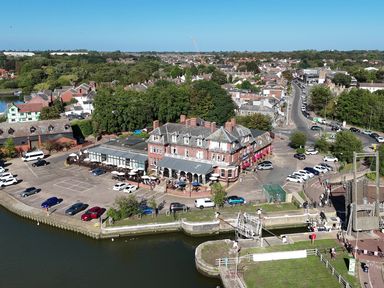 A building near a parking lot and river at The Mill House Apartment in Oulton Broad