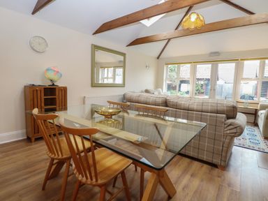 A dining area with a table, chairs and sofa at The Mill House Annexe Oulton Broad