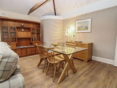 A dining room with a glass table and wooden chairs at The Mill House Annexe Oulton Broad