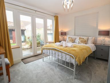 A bedroom with a bed and windows leading to an outdoor area at The Mill House Annexe Oulton Broad