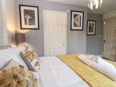 A bedroom with a bed, lamp, and artwork at The Mill House Annexe Oulton Broad