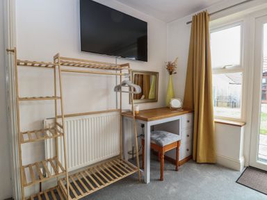 A bedroom with a table and chair next to a window at The Mill House Annexe in Oulton Broad