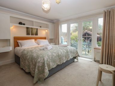 A bedroom with a bed and sliding doors leading to an outdoor area at The Mill House Annexe Oulton Broad