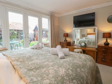 A bedroom with a bed and television at The Mill House Annexe Oulton Broad