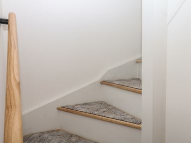 A staircase with wooden handrail at Elberry Cove View in Paignton