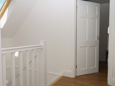 A hallway with a railing and an open door at Elberry Cove View in Paignton