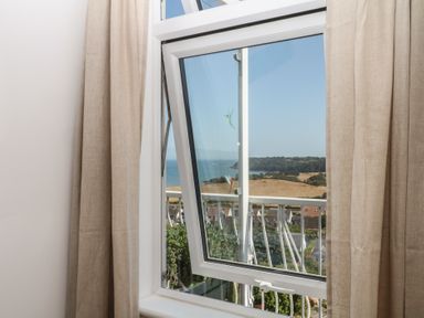 A window showing a view of the sea and landscape at Elberry Cove View in Paignton
