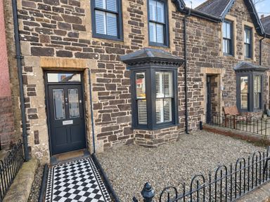 A front exterior view of a stone house with a gravel garden and bench in Rheidiol St Davids