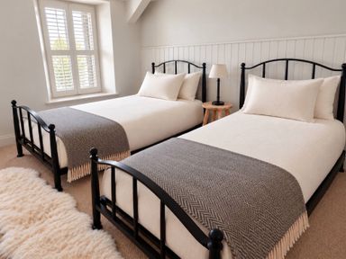 A bedroom with two beds and a side table at Rheidiol in St Davids