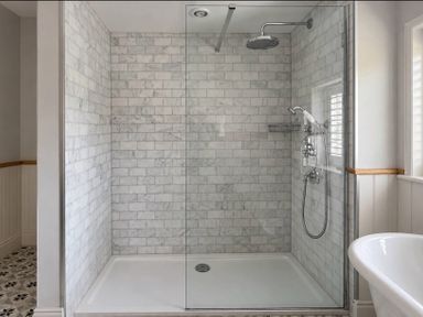 A shower with glass door and marble walls at Rheidiol in St Davids