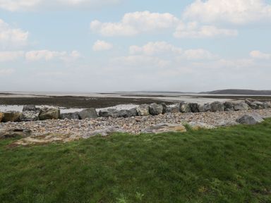 A shoreline with rocks and grass at Chalet 242 Carmarthen Bay Kidwelly