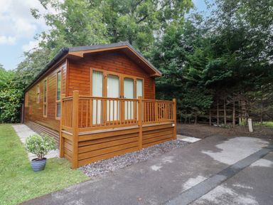 A wooden lodge with a porch and driveway at Fir Tree Lodge, White Cross bay on Windermere, Troutbeck Bridge