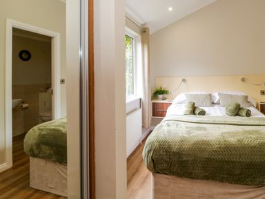 A bedroom with a bed and an adjoining bathroom at Fir Tree Lodge, White Cross bay on Windermere, Troutbeck Bridge