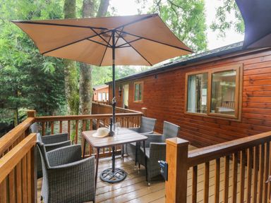 An outdoor seating area with a table and chairs at Fir Tree Lodge White Cross bay on Windermere Troutbeck Bridge