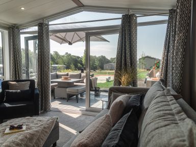 A living room with a sofa and armchair with outdoor views at Lakewood Plot 7 St. Osyth