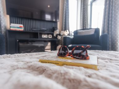 A living room with sunglasses and a book on a table at Lakewood Plot 7 in St. Osyth