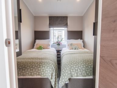 A bedroom with two beds and a window at Lakewood Plot 7 St. Osyth