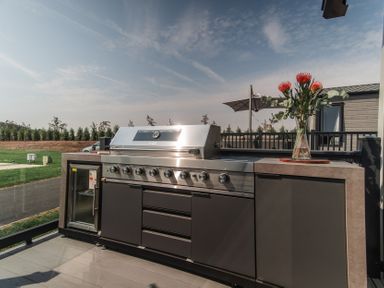 An outdoor kitchen with a grill and flowers in a vase at Lakewood Plot 7 St. Osyth