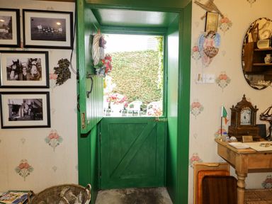 An entryway with a green door and photographs at Teresa's Cottage