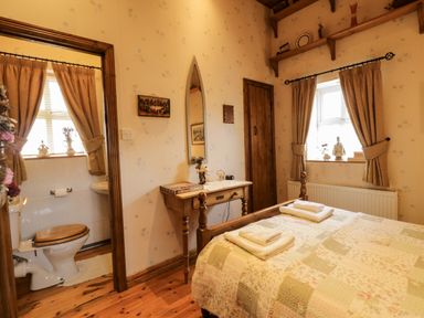 A bedroom with a bed and adjacent bathroom at Teresa's Cottage