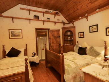 A bedroom with twin beds and a wooden cabinet at Teresa's Cottage