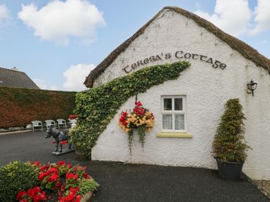 An exterior view of Teresa's Cottage with flowers and a horse statue in a garden