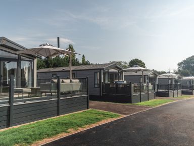 A row of static caravans with decking and umbrellas at Lakewood Plot 9 St. Osyth