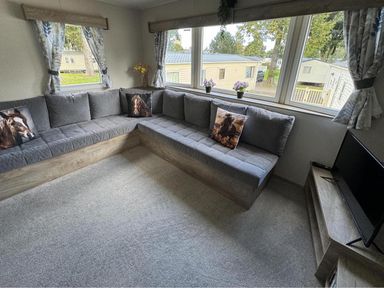 A living room with a corner sofa and television at West Lawn 47 Haggerston Castle Paddock Views Haggerston