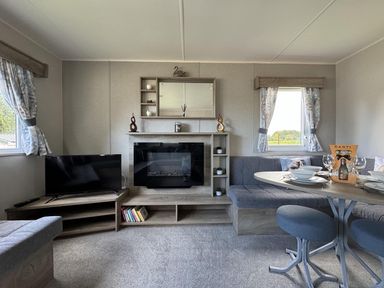 A living room with a sofa and television at West Lawn 47 Haggerston Castle Paddock Views Haggerston