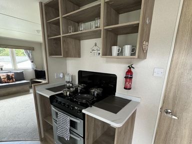 A kitchen with a stove and shelves at West Lawn 47 Haggerston Castle Paddock Views Haggerston