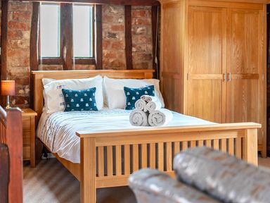 A bedroom with a bed, bedside table, and wardrobe at Barn Conversion Sleeps 2 with Parking in Diss