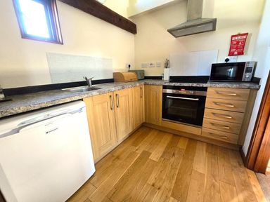 A kitchen with a sink, cabinets, microwave, and oven at Barn Conversion Sleeps 2 with Parking in Diss