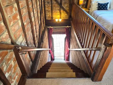 A staircase with wooden railings leading to a doorway at Barn Conversion Sleeps 2 with Parking in Diss