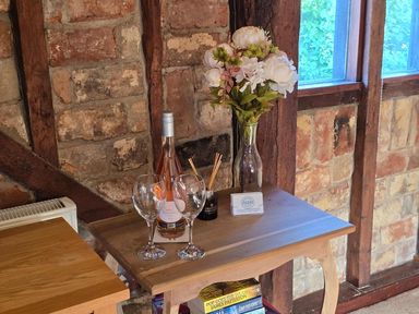 A table with wine, glasses and flowers at Barn Conversion Sleeps 2 with Parking in Diss