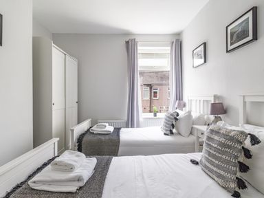 A bedroom with two beds and a wardrobe at East House-Sleeps 5-Pet friendly-Garden-Parking in Stakeford