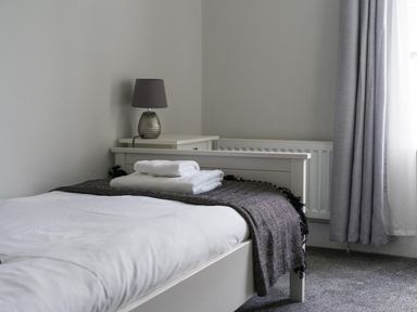 A bedroom with a bed, lamp, and towels at East House-Sleeps 5-Pet friendly-Garden-Parking in Stakeford