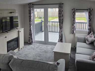 A living room with a television and fireplace at 3 Bedroom Cabin Sleeps 6 - Shared Pool & Shared Hot Tub, Flamingo Land Resort near Malton
