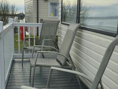 A seating area with chairs on a deck at Port Haverigg Cabin Sleeps 4, Steel Green near Haverigg