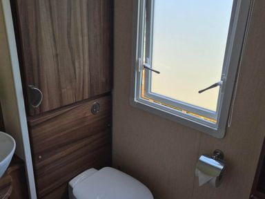 A bathroom with a toilet and window at Cabin - Sleeps 6 - Outdoor Pool and Parking Cenarth