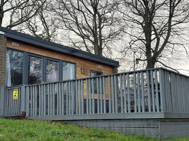 A lodge with a deck and windows at Pet Friendly 2-Bed Lodge, Sleeps 5, Pool & Parking, Caernarfon