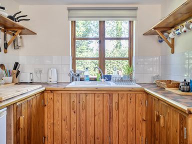 A kitchen with a sink and shelves at 3-Bed Barn Eco-Lodge on the Tarka trail, East Yarde near Great Torrington