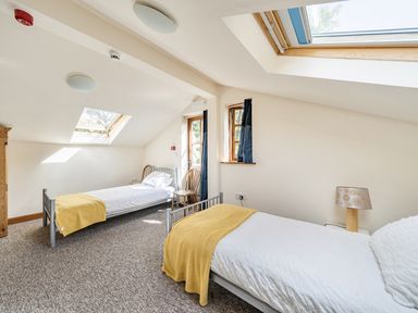 A bedroom with two beds and a lamp at 3-Bed Barn Eco-Lodge on the Tarka trail East Yarde near Great Torrington