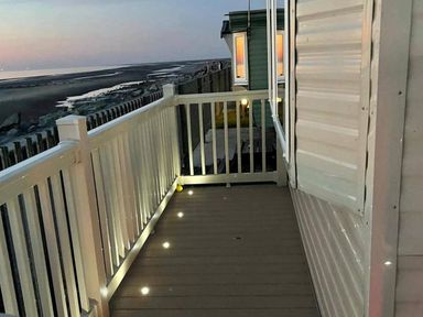 An outdoor area with a balcony and view of the beach at Seafront Caravan - Golden Sands - 6 Berth by Your Away Stays, Kinmel Bay