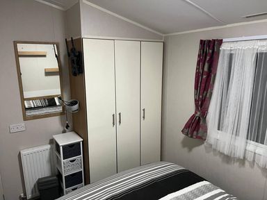 A bedroom with a bed, wardrobe, and mirror at Seafront Caravan - Golden Sands - 6 Berth by Your Away Stays in Kinmel Bay