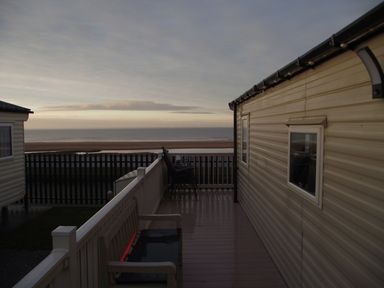 An outdoor area with a caravan and a view of the sea at Seafront Caravan - Golden Sands - 6 Berth by Your Away Stays in Kinmel Bay