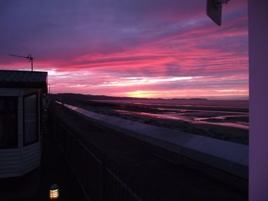 A sunset view with a caravan in the foreground at Seafront Caravan - Golden Sands - 6 Berth by Your Away Stays, Kinmel Bay