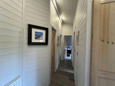 A hallway with wooden door and framed picture at Holly Blue - Cosy wooden lodge, Kippford