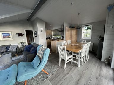 A dining room with a wooden table and chairs at Holly Blue - Cosy wooden lodge, Kippford