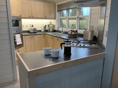 A kitchen with coffee cups and a coffee maker at Holly Blue - Cosy wooden lodge, Kippford